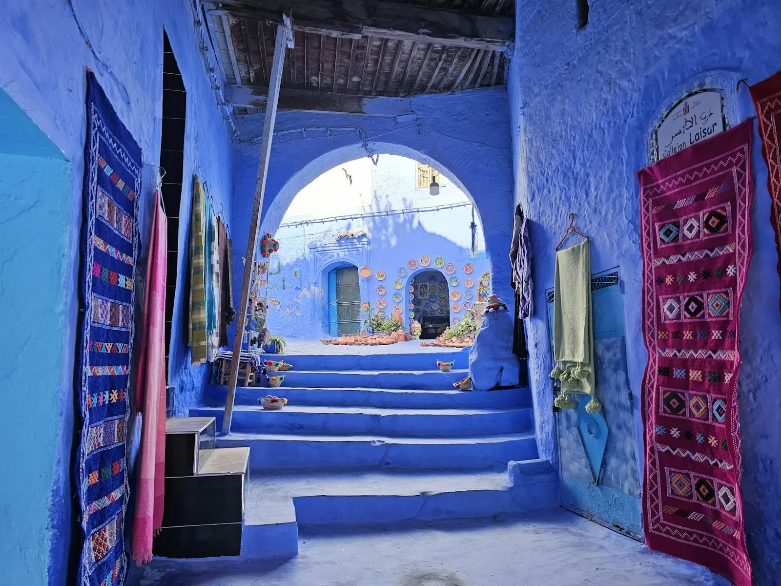 Blue alley with stairs and hanging rugs